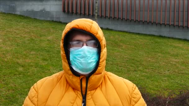 Adult man in medical mask with foggy glasses removes the hood — Stockvideo