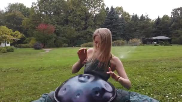 Músico ensaiando um jogo de enforcamento no jardim verde — Vídeo de Stock