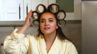 Mutfakta büyük bigudilere dokunan bir kadın.