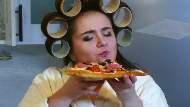 Nahaufnahme einer jungen Frau, die in ein Stück Pizza beißt — Stockvideo