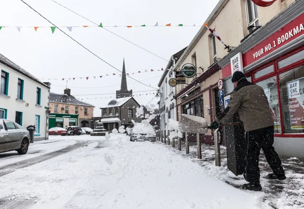 Mann schabt Schnee vor der Kneipe. lizenzfreie Stockfotos