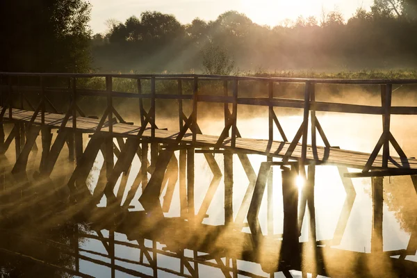 Puente de madera en el mar durante el amanecer — Foto de Stock