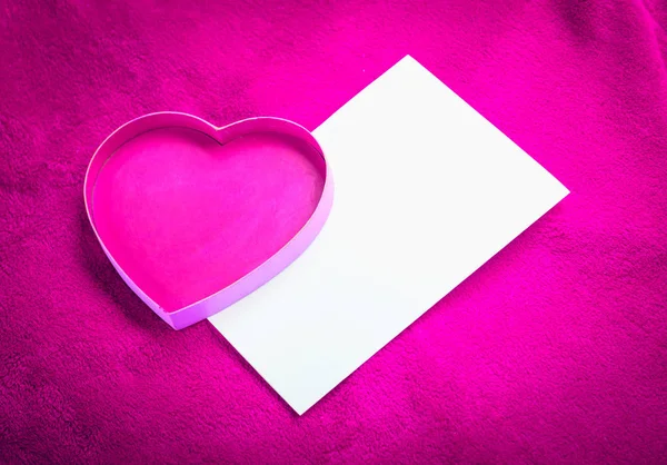 Corazón con una tarjeta en blanco sobre fondo rojo —  Fotos de Stock