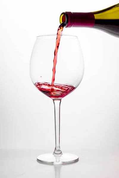 Rött vin som hälls i glas på vit bakgrund — Stockfoto