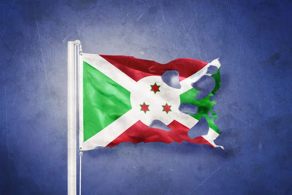 Torn flag of Burundi flying against grunge background — Stock Photo, Image