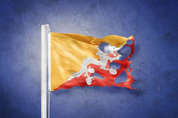 Sönderrivna flagga av Bhutan flyger mot grunge bakgrund — Stockfoto