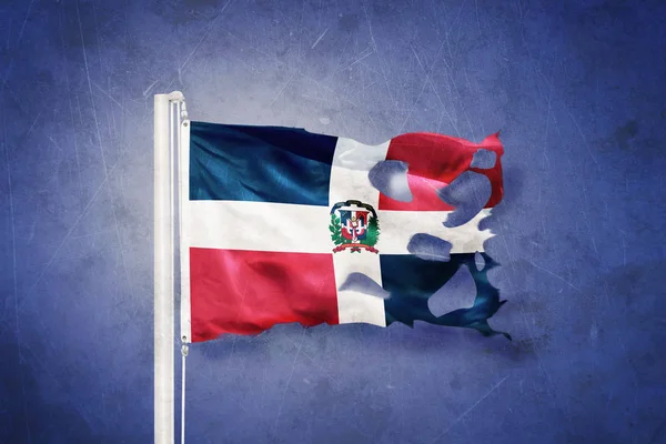 Bandeira rasgada da República Dominicana voando contra fundo grunge — Fotografia de Stock