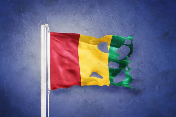 Torn flag of Guinea flying against grunge background — Stock Photo, Image