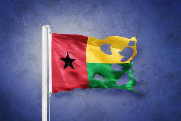 Bandeira rasgada da Guiné-Bissau voando contra fundo grunge — Fotografia de Stock