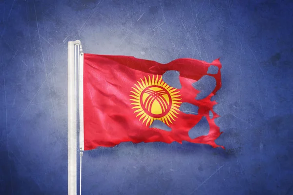 Sönderrivna flagga Kirgizistan flyger mot grunge bakgrund — Stockfoto