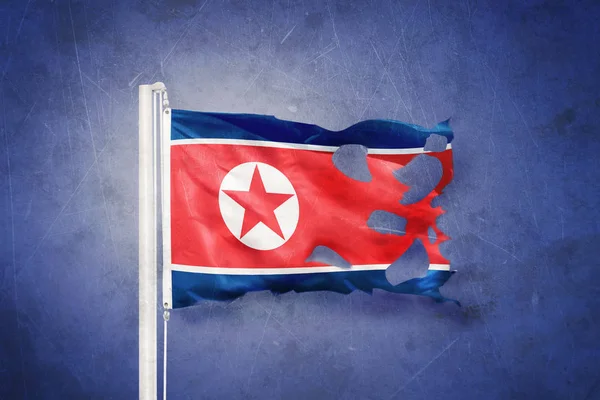 Bandeira rasgada da Coreia do Norte voando contra fundo grunge — Fotografia de Stock