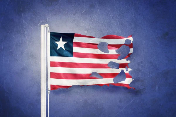 Gescheurde vlag van Liberia vliegen tegen grunge achtergrond — Stockfoto