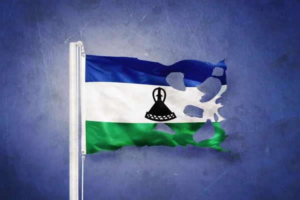 Bandeira rasgada do Lesoto voando contra fundo grunge — Fotografia de Stock