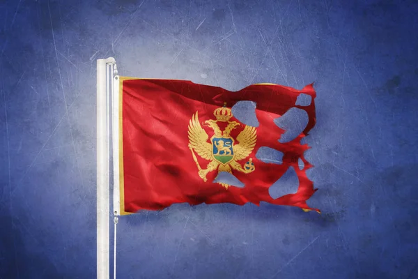 Torn flag of Montenegro flying against grunge background — Stock Photo, Image