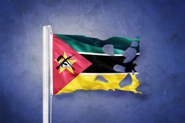 Gescheurde vlag van Mozambique vliegen tegen grunge achtergrond — Stockfoto