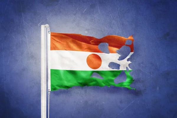 Torn flag of Niger flying against grunge background — Stock Photo, Image