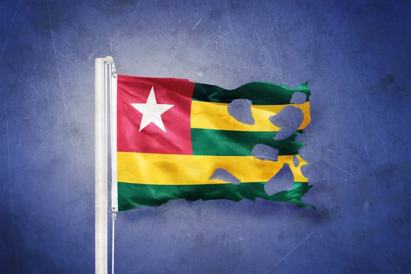 Gescheurde vlag van Togo vliegen tegen grunge achtergrond — Stockfoto