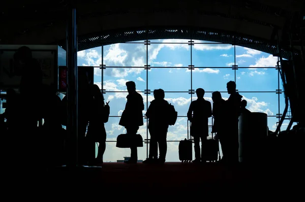 Silhouetten von Menschen, die am Flughafen auf ihren Flug warten — Stockfoto