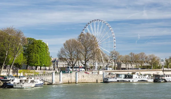 Parigi, 30 marzo 2017: Riverside a Parigi con ruota panoramica sul Concorde e battello passeggeri che porta i turisti in crociera sul fiume — Foto Stock