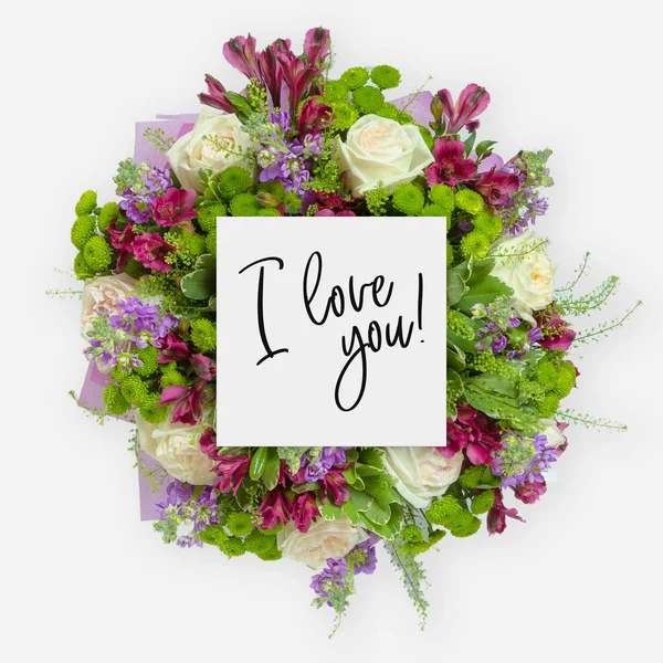 Färska blommor gäng och kort med orden jag älskar dig skrivet på det — Stockfoto