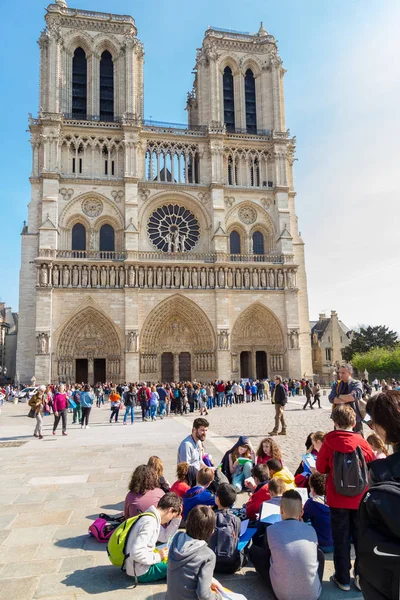 Paris, Frankrike, mars 27 2017: En grupp av barn med färgglada ryggsäckar på en resa till berömda Notre Dame katedralens fasad saint statyer. — Stockfoto