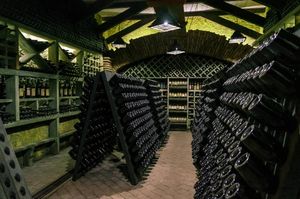 Bodega con botellas de vino. Viejas botellas de vino cubiertas de polvo y telarañas se encuentran en la bodega de la bodega. Bebida alcohólica almacenamiento vintage — Foto de Stock