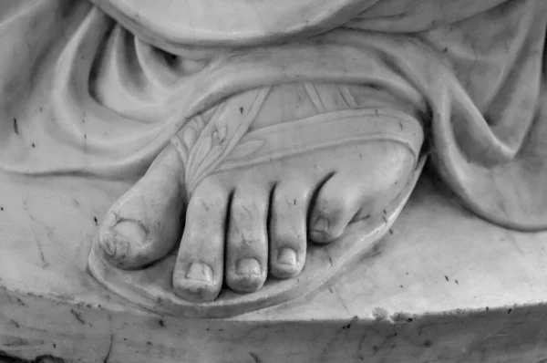 Pied. Fragment d'une statue en marbre antique. Terrain fissuré en arrière-plan. Membre en plâtre, pied mâle avec les doigts, partie du corps. Pieds de statue de granit antique de l'homme isolé sur fond blanc — Photo