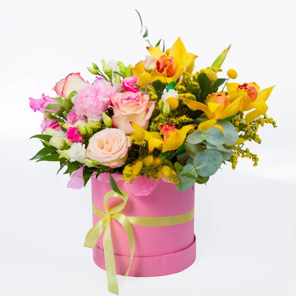 모자 상자에 있는 꽃, 장미와 난초를 선물로 받은 소녀를 위한 핑크 남비. 하얀 배경에 따로 떨어져 있는 원통 모양의 분홍색 상자 안에 아름다운 꽃들 이 꽃다발을 이루고 있다 스톡 사진
