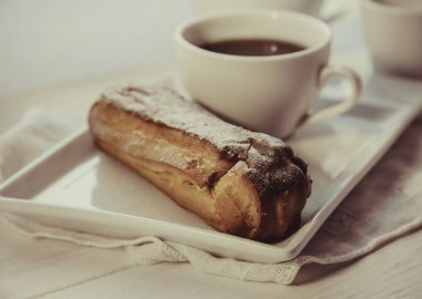 Tabakta çikolatalı ekler ve bir fincan kahve.