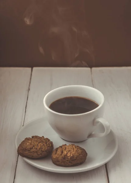 Чашка горячего эспрессо и печенья на деревянном столе — стоковое фото