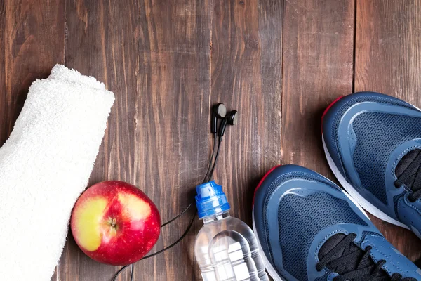 Spor ayakkabı, su, havlu ve ahşap masa üzerinde kulaklık — Stok fotoğraf