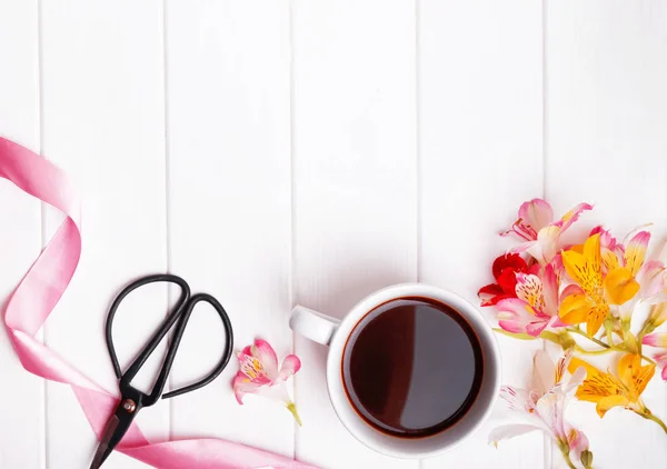 Flowers, coffee, scissors and pink ribbon on the white table — Stock Photo, Image