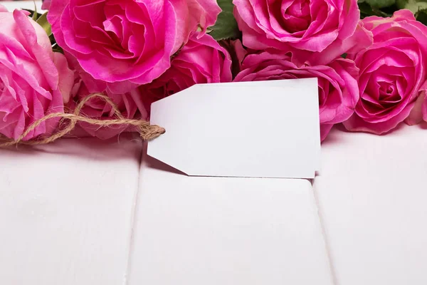 Beautiful pink roses and empty paper tag — Stock Photo, Image