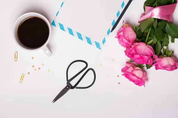 Bouquet of pink roses, coffee, blank paper  and other objects