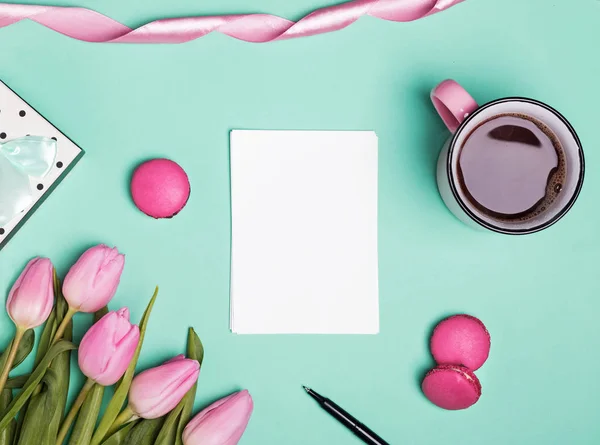 Papel em branco, tulipas rosa, macarons e café em uma caneca — Fotografia de Stock