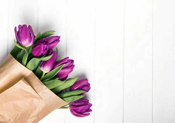 Roze tulpen verpakt in Kraft papier op de witte tafel — Stockfoto