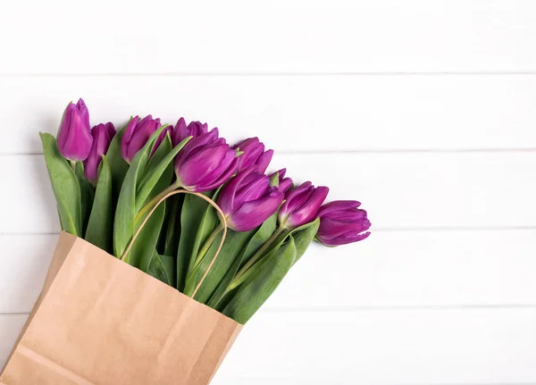 Roze tulpen in een papieren zak op de witte houten tafel — Stockfoto