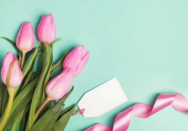 Růžové tulipány, pásu karet a prázdné dárkové tag na pastelově zelené poza — Stock fotografie