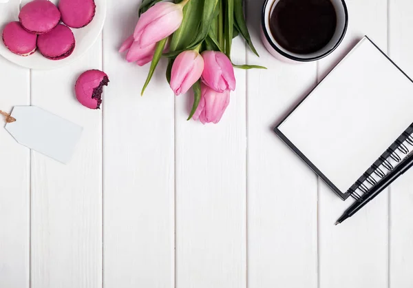 Розовые тюльпаны, макароны, пустой блокнот и кофе на белом дереве — стоковое фото