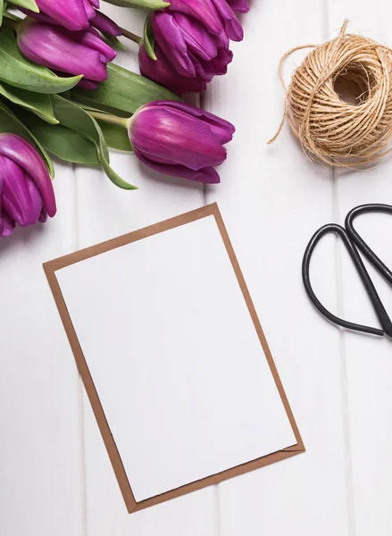 Mock-up met blanco papier en paarse tulpen op de witte tafel — Stockfoto