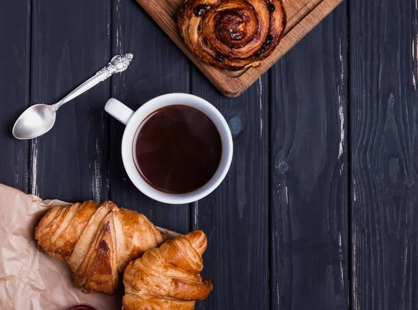 Croissants y café en la mesa de madera negra — Foto de Stock