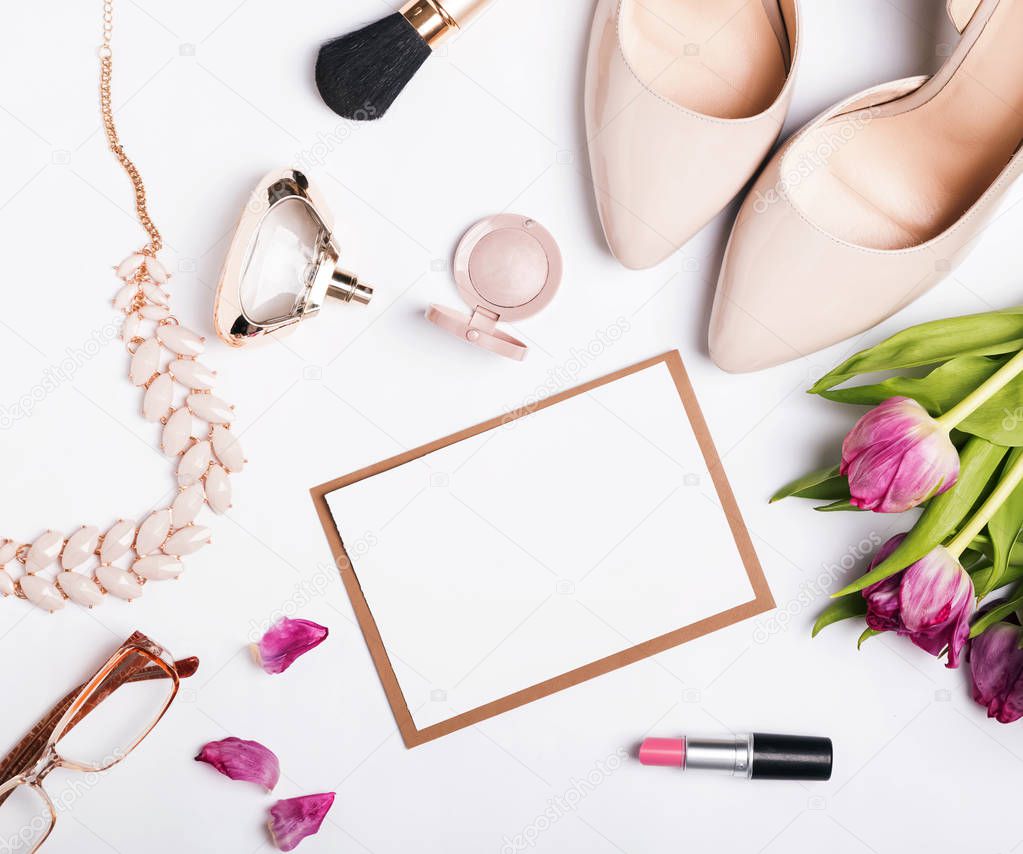 Woman's accessories of beige color, pink tulips and blank paper 