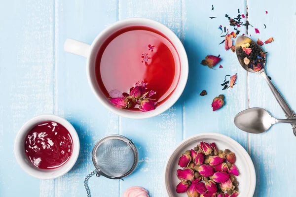 Herbal tea and dry roses on blue colored table — Stock Photo, Image