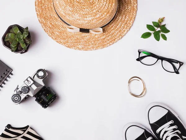 Straw hat, sneakers, vintage camera and other outfit on white ba