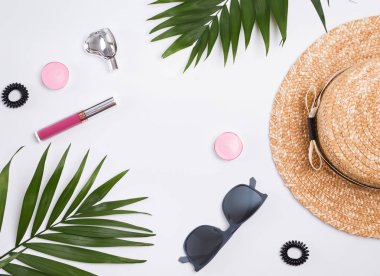 Hasır şapka, güneş gözlüğü ve palmiye yaprakları beyaz arka plan üzerinde.