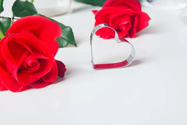 Rosas rojas y molde de metal en forma de corazón en el backgorund blanco —  Fotos de Stock