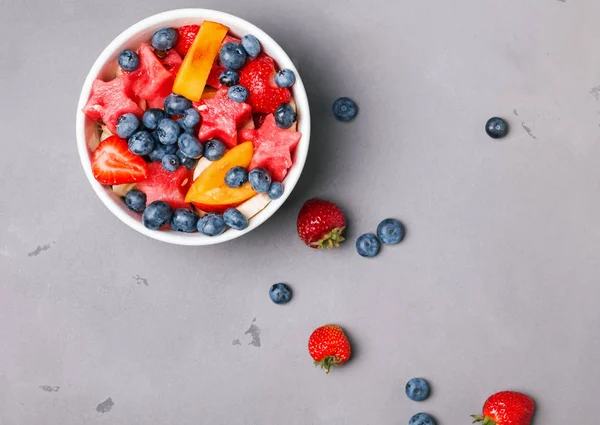 Frutta e bacche nella ciotola sullo sfondo grigio — Foto Stock