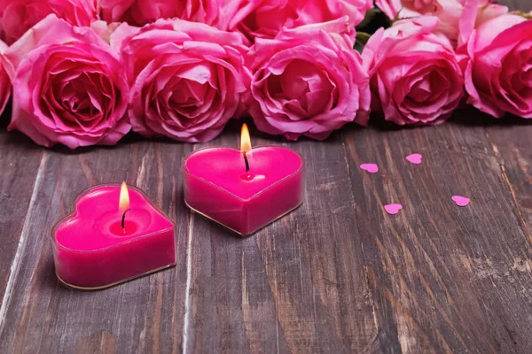 两个燃烧的蜡烛和美丽的粉红色玫瑰在木 backg — 图库照片