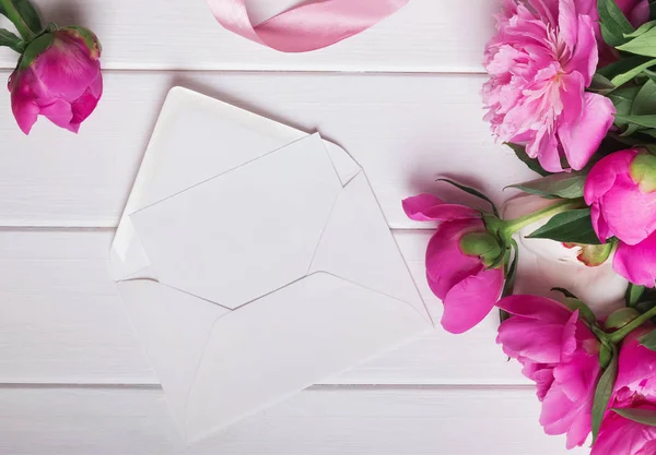 Beautiful peonies and blank paper in envelope — Stock Photo, Image