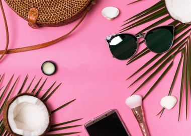 Kadınsı tatil aksesuarları üzerinde pembe bir arka plan, üstten görünüm